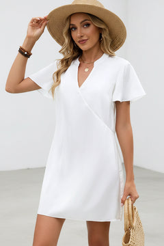 White satin mini dress with V-neck and flutter sleeves, draped wrap front