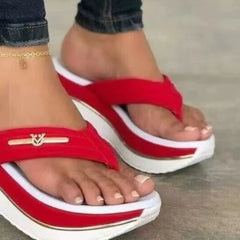 Red platform toe-post sandals with gold logo bar on the strap and white platform sole.