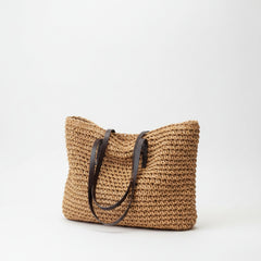 Woven straw tote bag, tan woven straw with dark brown trim and loop handles.