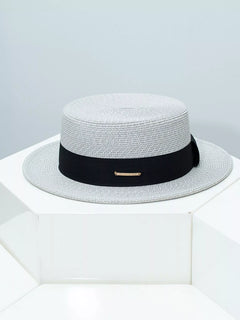 Light gray straw boater hat with black ribbon band and gold bar detail