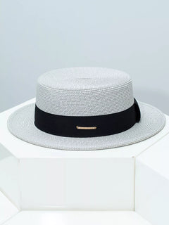 Light gray straw boater hat with black ribbon band and gold bar detail