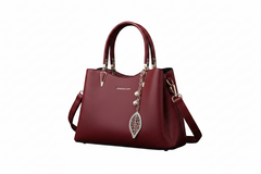 Red leather top-handle handbag with strap, gold hardware, leaf charm, structured base