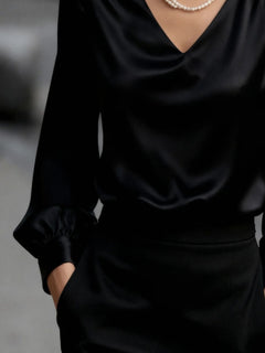 Black satin V-neck puff sleeve blouse, close-up of neckline and hemline
