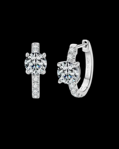 Pair of silver hoop earrings with clear gemstones on a black background