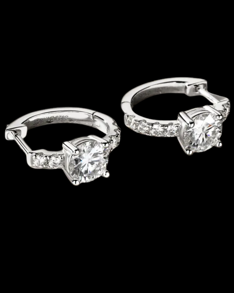 Pair of silver hoop earrings with clear gemstones on a black background
