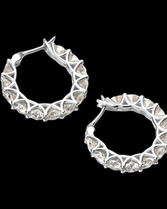 Pair of silver hoop earrings with clear gemstones on a black background