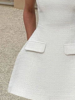 White mini dress close-up of front flap pockets on textured fabric